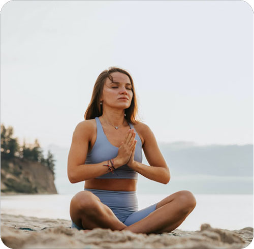 Una mujer practicando la meditacion en la playa